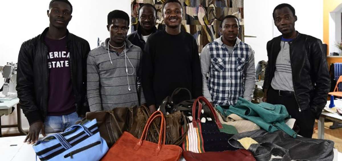 Bassirou (el tercero, de izq. a der.) muestra los bolsos que confecciona en Lai Momo, un programa que capacita a los migrantes que llegan a Italia.
