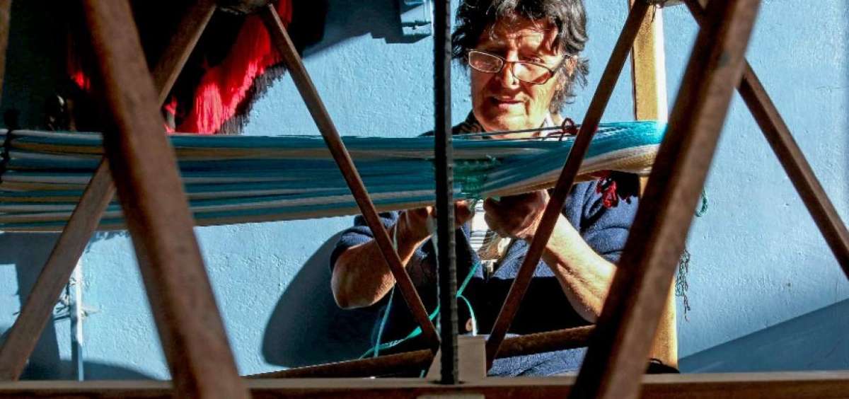 Blanca Rodas coloca las madejas de hilo en una estructura de madera, donde forma los dise&ntilde;os.     