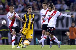 Leonardo Ponzio (der.), de River Plate, despeja el bal&oacute;n ante la marca de Juli&aacute;n Ben&iacute;tez (centro) de Guaran&iacute;, anoche en el estadio Monumental. Foto: AFP