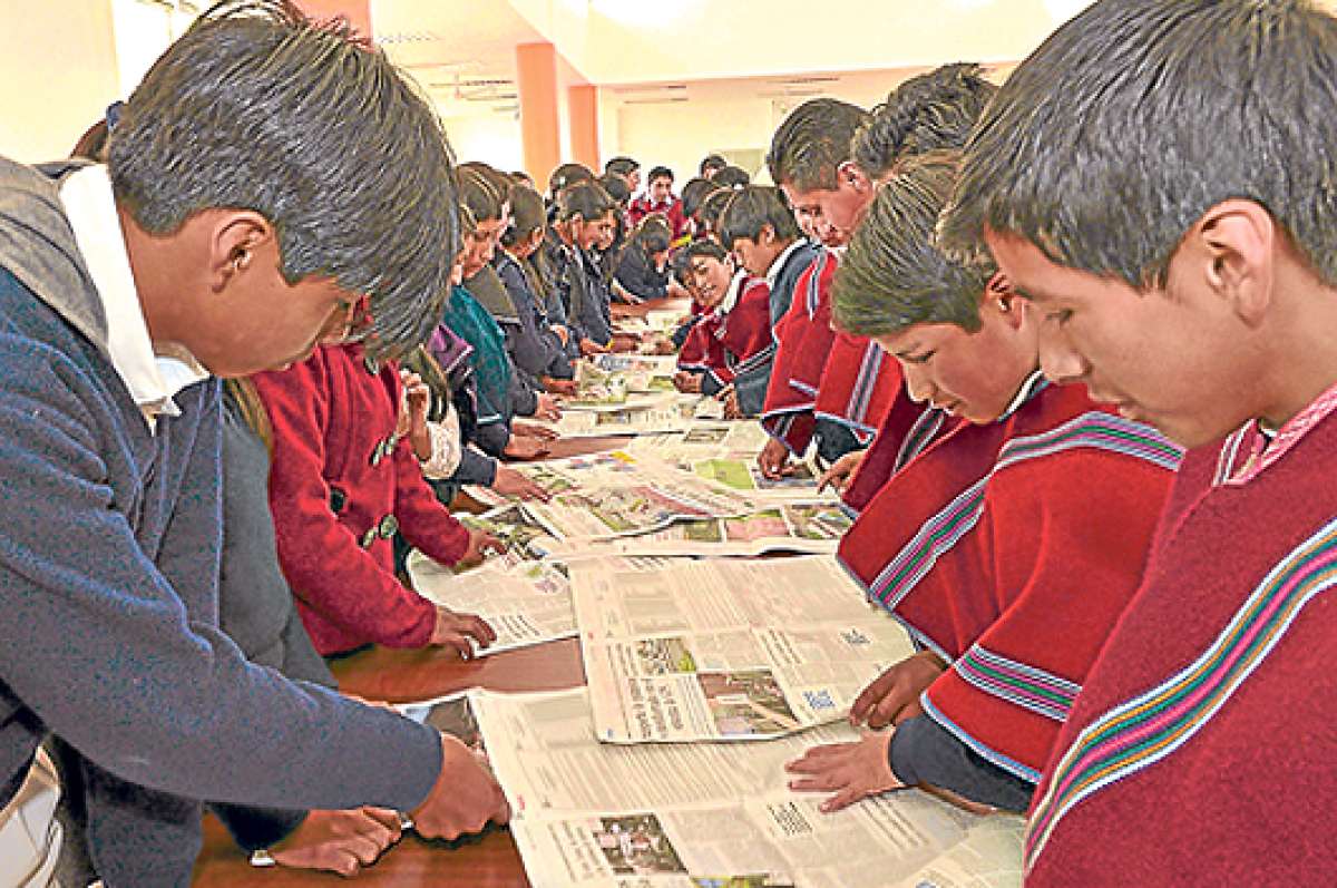 Estudiantes, vestidos con sus t&iacute;picos ponchos rojos a rayas, observan ejemplares de  EL TEL&Eacute;GRAFO durante las clases del Club de Periodismo. Foto:  Roberto Ch&aacute;vez / El Tel&eacute;grafo.