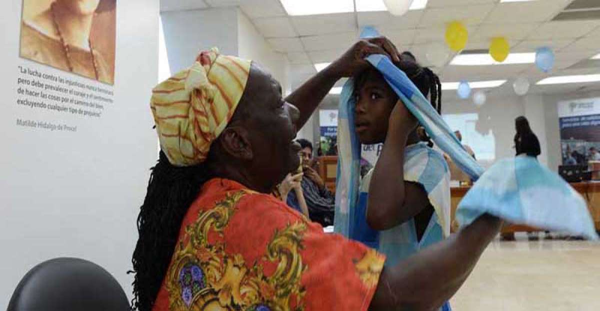 Angela Lastra coloca el turbante a su nieta Danna, de 9 a&ntilde;os. Ellas recordaron el D&iacute;a de la Mujer Afrodescendiente.