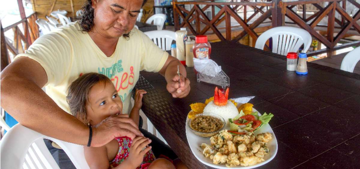 La peque&ntilde;a Coralia disfruta los camarones que su padre, Tito Parrales, le da de comer.