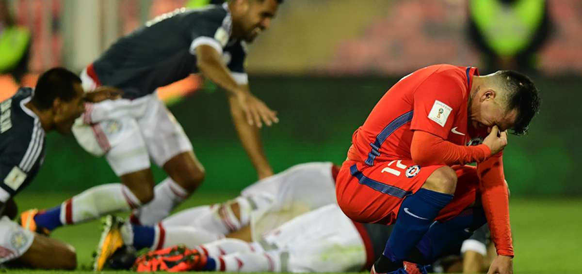 El defensa de la selecci&oacute;n chilena, Gary Medel (d) se lamenta de rodillas mientras los jugadores paraguayos celebran la goleada que le propinaron a los bicampeones de Am&eacute;rica.  