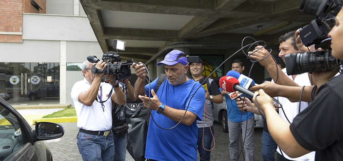 Rodrigo Figueroa (azul), preparador f&iacute;sico de la selecci&oacute;n ecuatoriana, abandona el edificio de la Ecuaf&uacute;tbol mientras los periodistas buscan una declaraci&oacute;n.