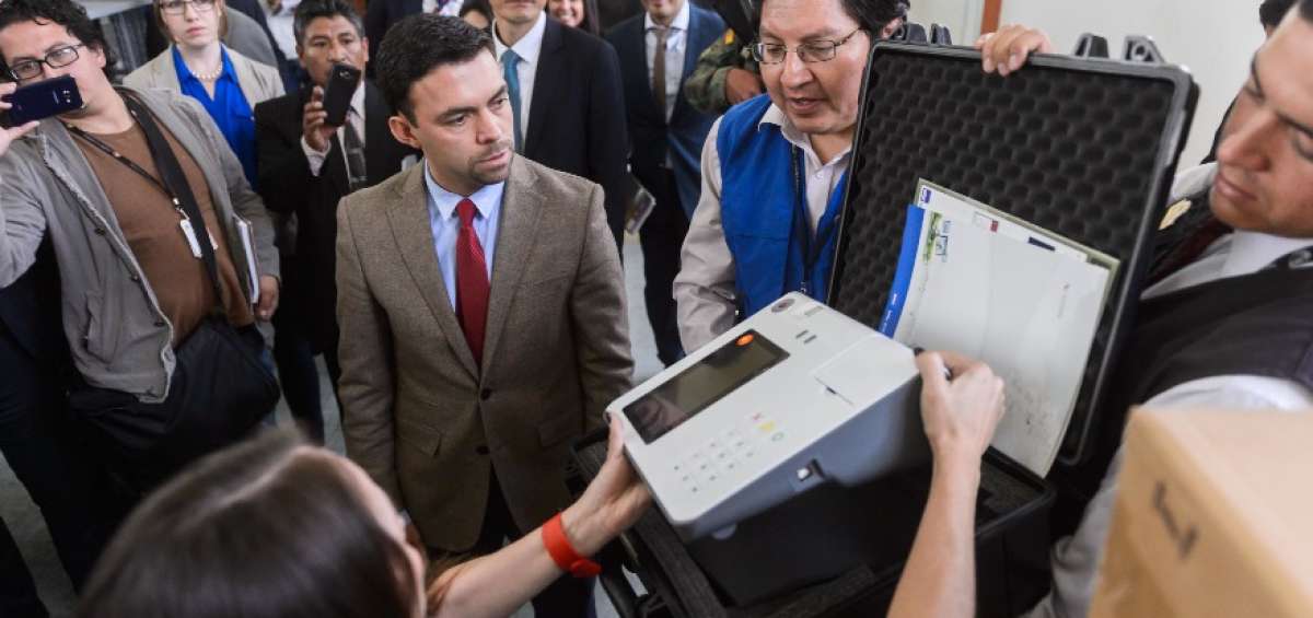 El director nacional de Inform&aacute;tica del CNE, Marcelo Olivo (azul), explica el funcionamiento de los equipos.