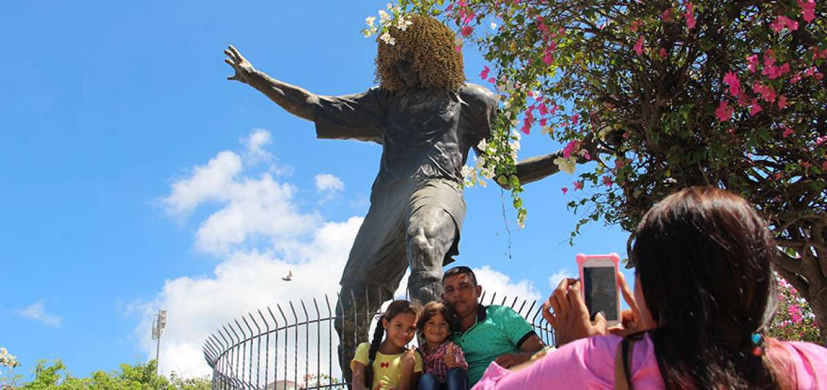 &rarr;Una familia se saca una fotograf&iacute;a con la escultura de uno de los samarios m&aacute;s ilustres, Carlos Valderrama. La figura est&aacute; ubicada junto al estadio Eduardo Santos y su visita est&aacute; incluida en los tours tur&iacute;sticos de varias empresas.  