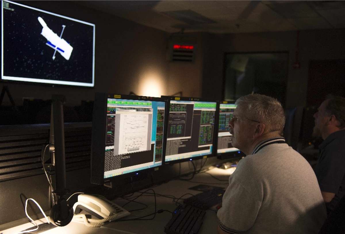 Dos hombres miran vigilan en trabajo del telescopio espacial Hubble en el Centro de control de la NASA. FOTO: AFP 