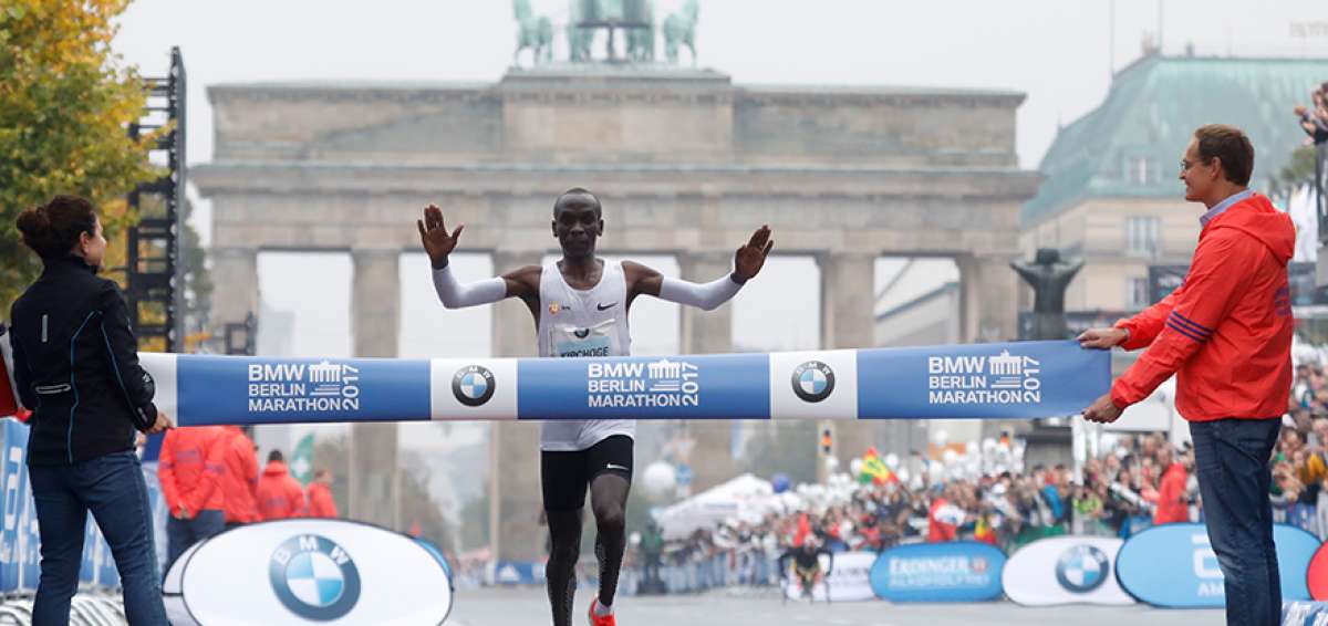 El maratonista keniano Eliud Kipchoge cruza la meta de la marat&oacute;n de Berl&iacute;n, detr&aacute;s de la Puerta de Brandeburgo, uno de los &iacute;conos de la ciudad alemana. 