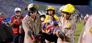 Una aficionada es atendida por los bomberos en el estadio Nacional, durante los incidentes que se desataron antes del cl&aacute;sico de Honduras.
