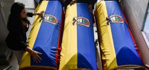 Un grupo de personas colocan banderas de Ecuador sobre los ataudes con los cuerpos de los tres integrantes del equipo de prensa del diario El Comercio, secuestrados en marzo pasado y posteriormente asesinados, en una funeraria en Cali, Colombia.