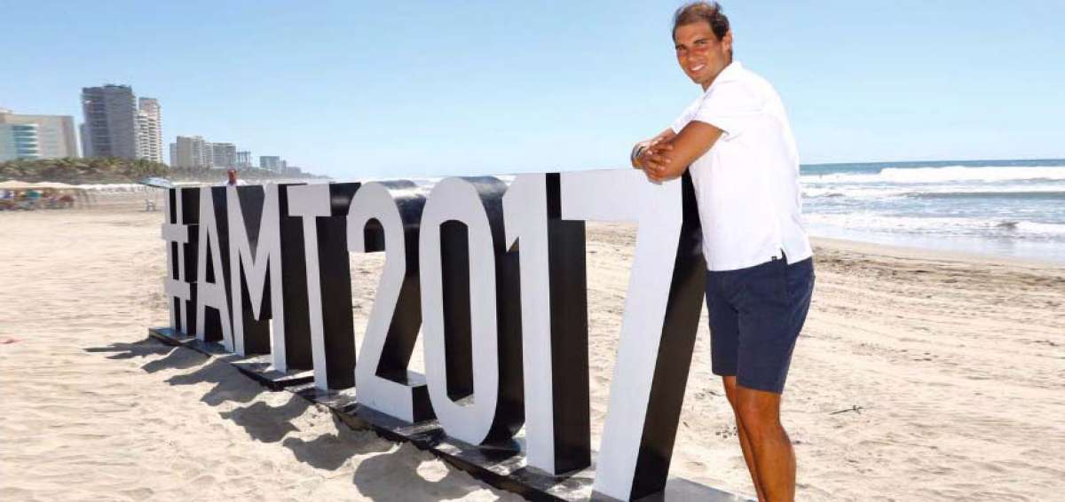 El espa&ntilde;ol Rafael Nadal posa con una imagen promocional del Abierto de M&eacute;xico, en las playas de Acapulco.  