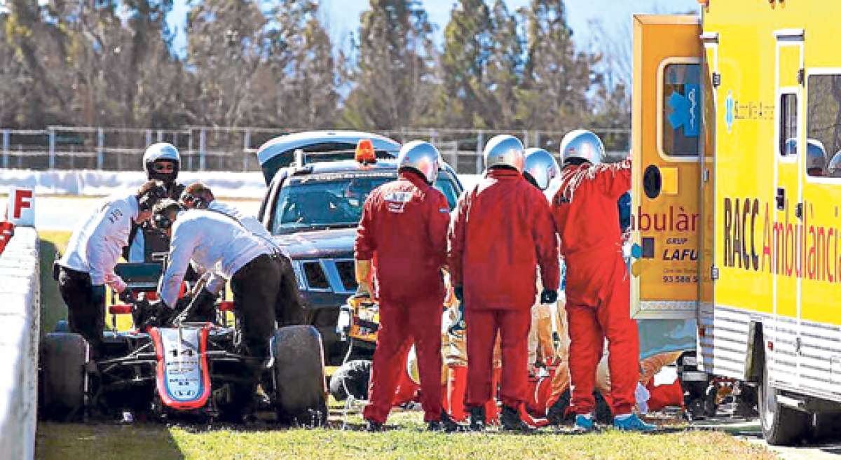 T&eacute;cnicos del equipo revisan el coche accidentado y param&eacute;dicos dan los primeros auxilios al piloto espa&ntilde;ol Fernando Alonso, antes de su ingreso al hospital. Foto: Internet