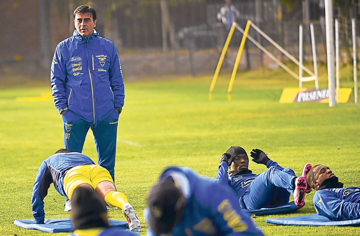 El estratega Gustavo Quinteros (de pie) observa el estiramiento de varios jugadores de la Tricolor -ayer- despu&eacute;s del entrenamiento en la cancha principal del complejo deportivo de Colo Colo, en Santiago. Foto: AFP