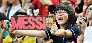 Una aficionada del Barcelona de Espa&ntilde;a, en un estadio de China, muestra un cartel con el nombre de Messi y el escudo del equipo catal&aacute;n.