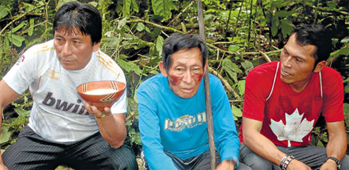 Tres miembros de la comunidad achuar de Copataza comparten un pilche de chicha preparado por las mujeres del lugar. Esa bebida fermentada la consumen a diario. Foto: Cortes&iacute;a| Octavo Arte.