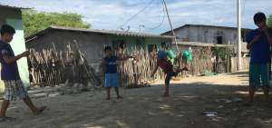 Jordy Medina Anastacio, de siete a&ntilde;os y gorra azul, juega junto con sus vecinos.  Los tres amigos muestran sus habilidades con el trompo al hacerlo bailar sobre las calles de tierra de su comuna.