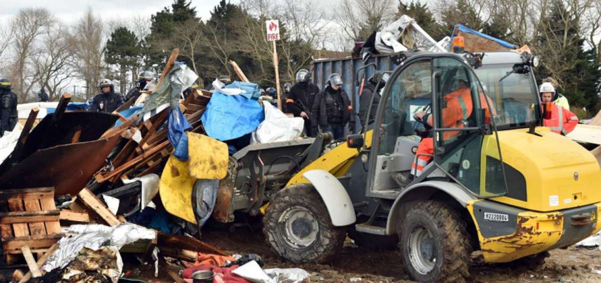 Operarios usan excavadoras para desmantelar el campamento de refugiados en Calais, Francia.  