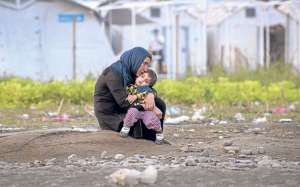 Una migrante siria arrulla a su hijo mientras espera para inscribirse en un campamento de Macedonia, despu&eacute;s de cruzar la frontera griega. Foto: AFP