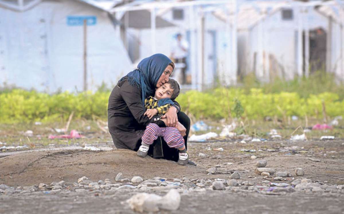 Una migrante siria arrulla a su hijo mientras espera para inscribirse en un campamento de Macedonia, despu&eacute;s de cruzar la frontera griega. Foto: AFP
