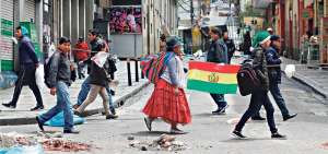 Los bolivianos caminan por una de las calles c&eacute;ntricas donde los ingresos a Plaza Murillo est&aacute;n bloqueados, en La Paz. La Polic&iacute;a boliviana retomar&aacute; el control, pero la ola de violencia contin&uacute;a.