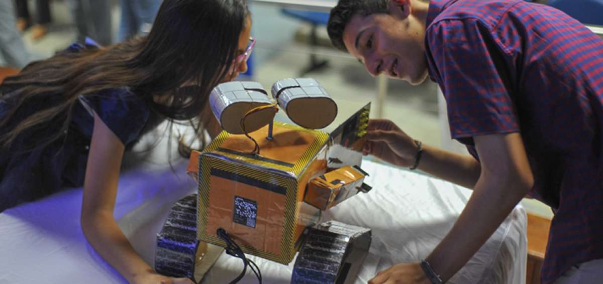 Ambos menores observan el robot que fue creado por Emily Ulloa luego de la charla que ofrecieron a inicios de la presente semana en Manta.