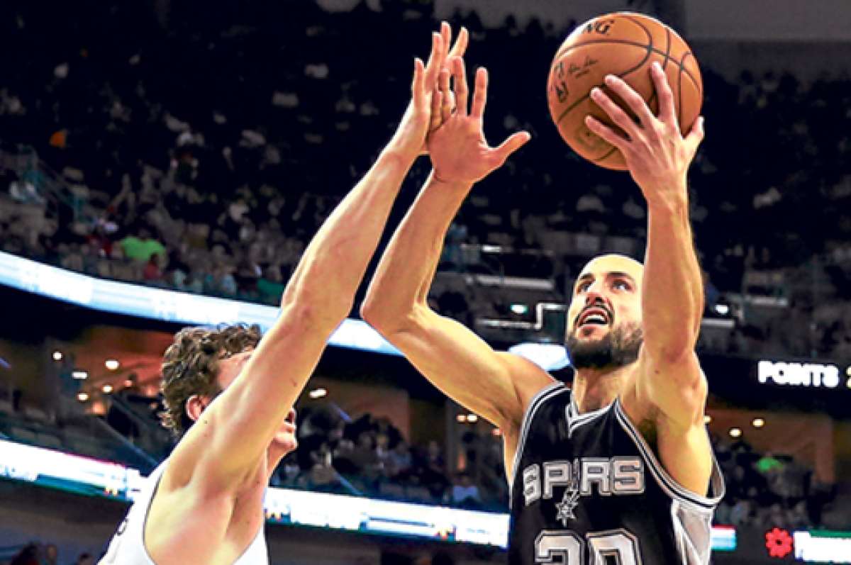 El argentino Emanuel Gin&oacute;bili intenta encestar ante la marca de un jugador de los Houston Rockets, la noche del domingo pasado en San Antonio. Foto: AFP