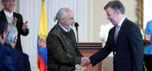 El presidente colombiano, Juan Manuel Santos, estrecha la mano del escritor Alfredo Molano (izq) durante la instalaci&oacute;n de la Comisi&oacute;n.