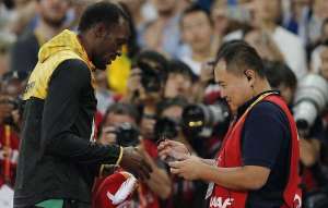 Son Tao, c&aacute;mara de la televisi&oacute;n CCTV, se acerc&oacute; t&iacute;midamente a Bolt, ambos se estrecharon las manos y el periodista le entreg&oacute; al atleta una pulsera para pedir excusas por lo ocurrido. Foto: Agencia AFP
