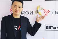 Justin Sun junto a la polémica obra de arte de la banana pegada con cinta adhesiva.
