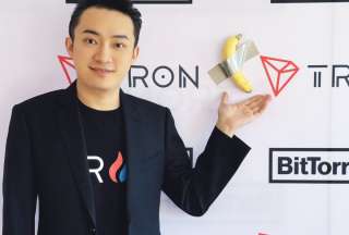 Justin Sun junto a la polémica obra de arte de la banana pegada con cinta adhesiva.