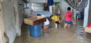 Tres menores sacan con baldes el agua que se les meti&oacute; a la casa en el sector de el Vergel, en Chone.
