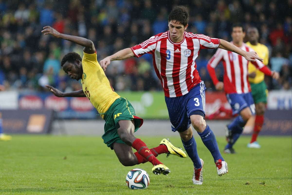 El camerun&eacute;s Edgar Salli disputa el bal&oacute;n con el paraguayo Danilo Ort&iacute;z. Foto: AFP