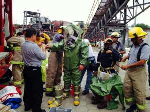 Con m&aacute;scaras y trajes que cubren todo el cuerpo, los expertos trabajan en la terminal portuaria. Foto tomada del Twitter @cups_fire_gye