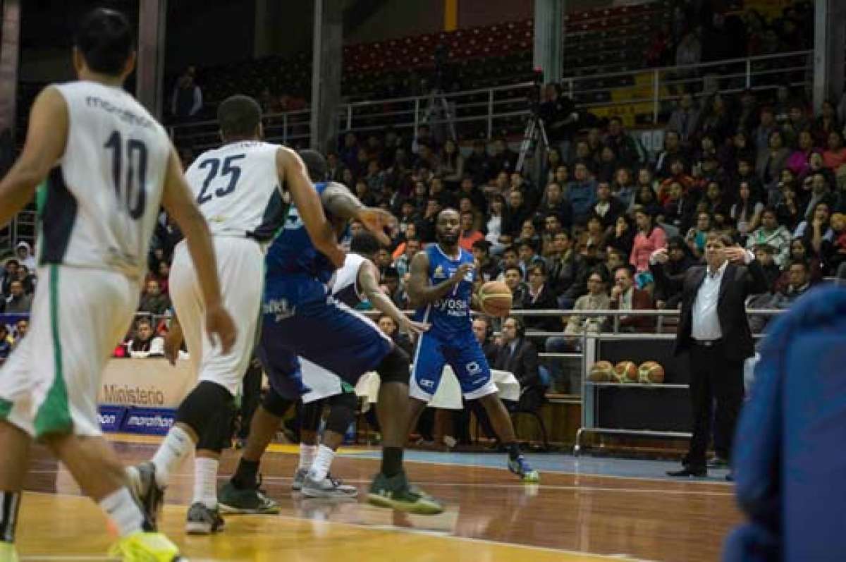 El estadounidense Scott Rodgers (centro) de CKT traslada el bal&oacute;n durante la primera final de la Liga Nacional de Baloncesto contra la UTE en Quito. Foto: John Guevara / El Tel&eacute;grafo.
