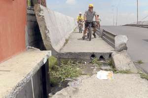 Juan D&aacute;vila y su hijo Gustavo (de amarillo) a diario conducen con precauci&oacute;n para no caer por el agujero que hay en el puente de la G. Foto: Lylibeth Coloma.