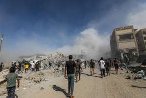 Los palestinos pasan junto a los escombros mientras el humo se eleva del edificio residencial al-Roya tras un ataque aéreo israelí en el oeste de la ciudad de Gaza, Franja de Gaza, 8 de septiembre de 2025.