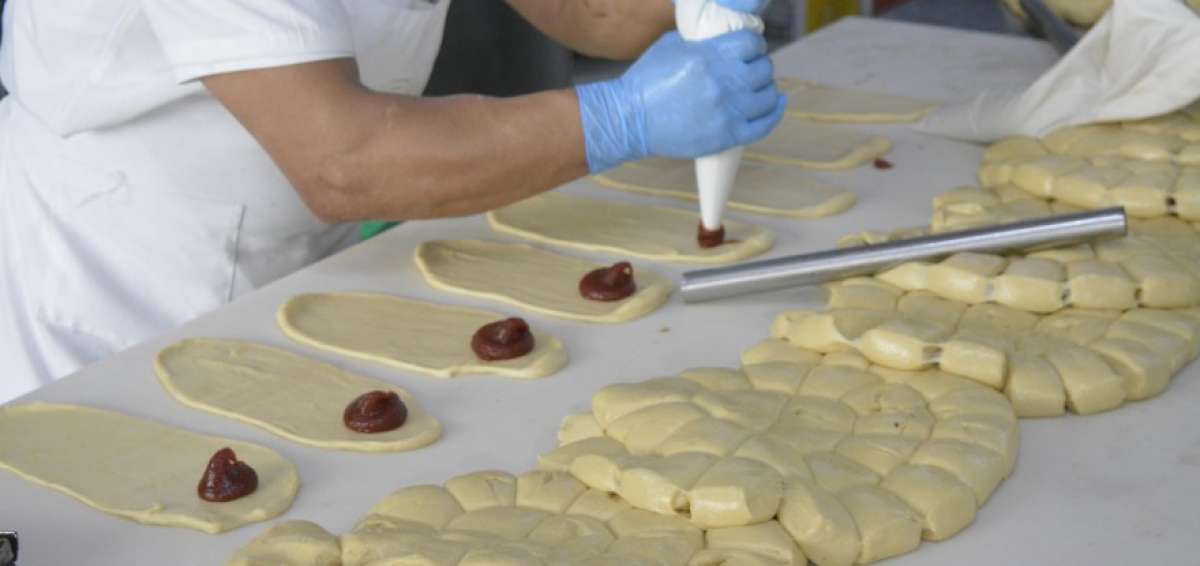 Un pastelero pone el relleno de dulce de guayaba en la masa preparada para las "guaguas de pan", en Quito.