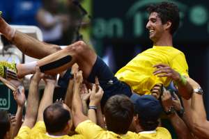 Thomaz Bellucci es levantado por sus compa&ntilde;eros de equipo luego de lograr el punto decisivo para Brasil. Foto: AFP