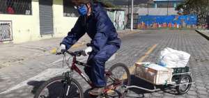 Uno de los distribuidores, equipado con traje de bioseguridad, usa una bicicleta para trasladar las provisiones hasta los hogares de las familias. 