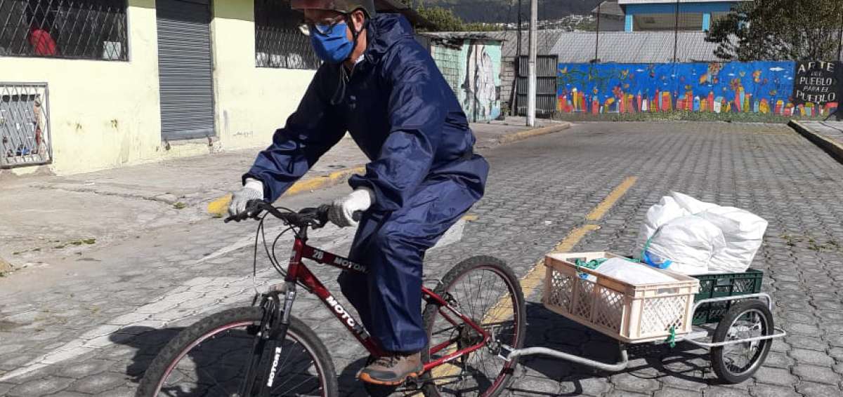 Uno de los distribuidores, equipado con traje de bioseguridad, usa una bicicleta para trasladar las provisiones hasta los hogares de las familias. 