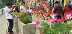 Una pareja aprovecha el arte urbano, desplegado en uno de los muros de antiguas f&aacute;bricas, para fotografiarse el d&iacute;a de su boda. Cafeter&iacute;as y galer&iacute;as  han recuperado una de las &aacute;reas de Pek&iacute;n que antes luc&iacute;an abandonadas.