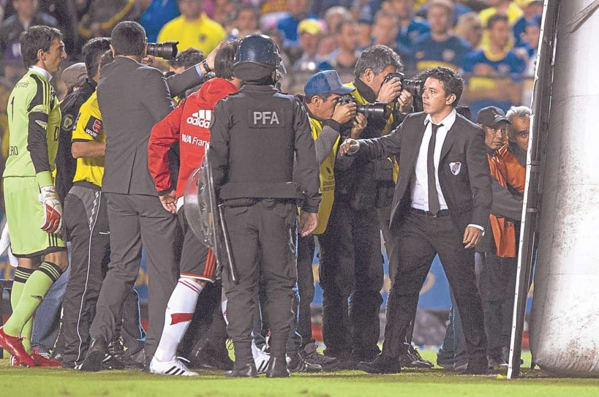 El t&eacute;cnico Marcelo Gallardo (der.) intenta controlar a sus jugadores minutos despu&eacute;s de que les lanzaran gas pimienta cuando se aprestaban para entrar a la cancha, luego del entretiempo. Fotos: AFP