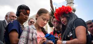 Greta Thunberg (i) firma una tarjeta a la activista paname&ntilde;a Militza Flaco (d) frente al Tribunal Supremo de Washington (Estados Unidos).
