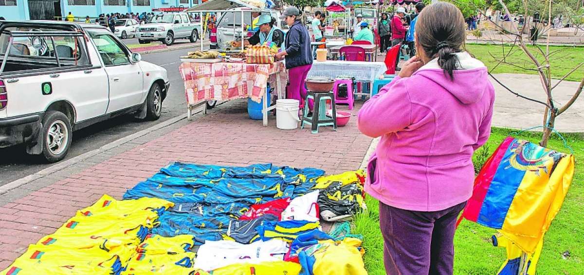 Vendedores de camisetas y banderas y comerciantes de comida se ubican en la parte exterior del estadio Ol&iacute;mpico de Riobamba antes de los partidos.