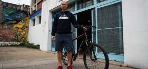El bioqu&iacute;mico Alejandro Mar&iacute;n Men&eacute;ndez posa con su bicicleta en la entrada de un liceo de Montevideo (Uruguay).