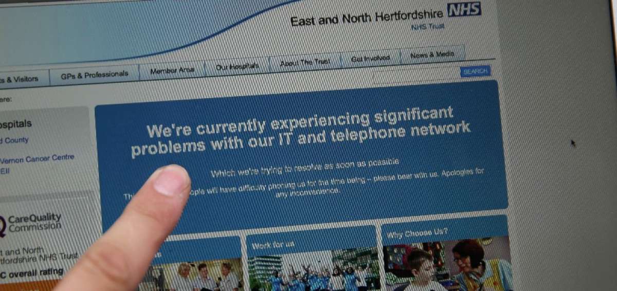 Un usuario muestra el sitio web del Servicio Nacional de Sanidad de Inglaterra con la notificaci&oacute;n de problemas. 
