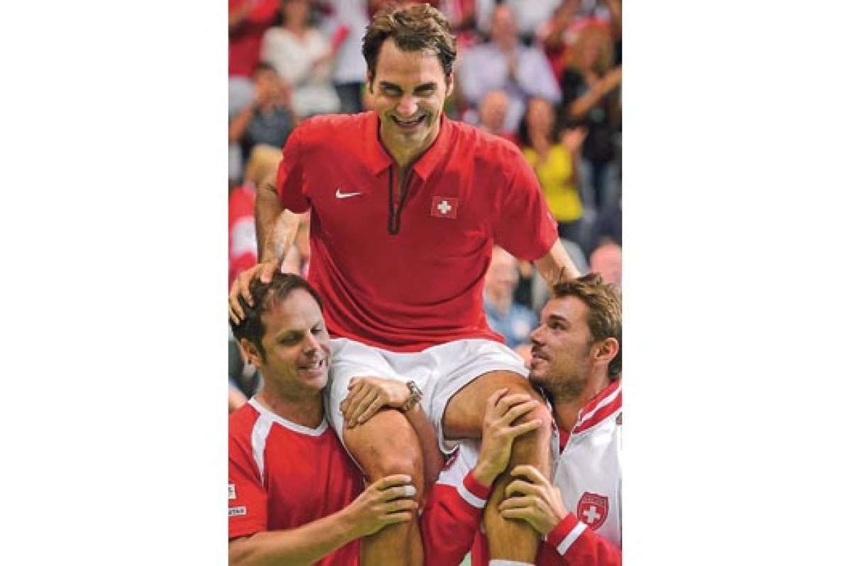 El capit&aacute;n del elenco suizo, Severin L&uuml;thi (izq.), y la segunda raqueta de este pa&iacute;s, Stanislas Wawrinka, sostienen en sus hombros a Roger Federer. Foto: Afp