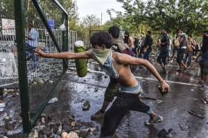 Migrantes tratan de tumbar una puerta en los enfrentamientos con polic&iacute;as antidisturbios en la frontera de Hungr&iacute;a con Serbia. Foto: AFP