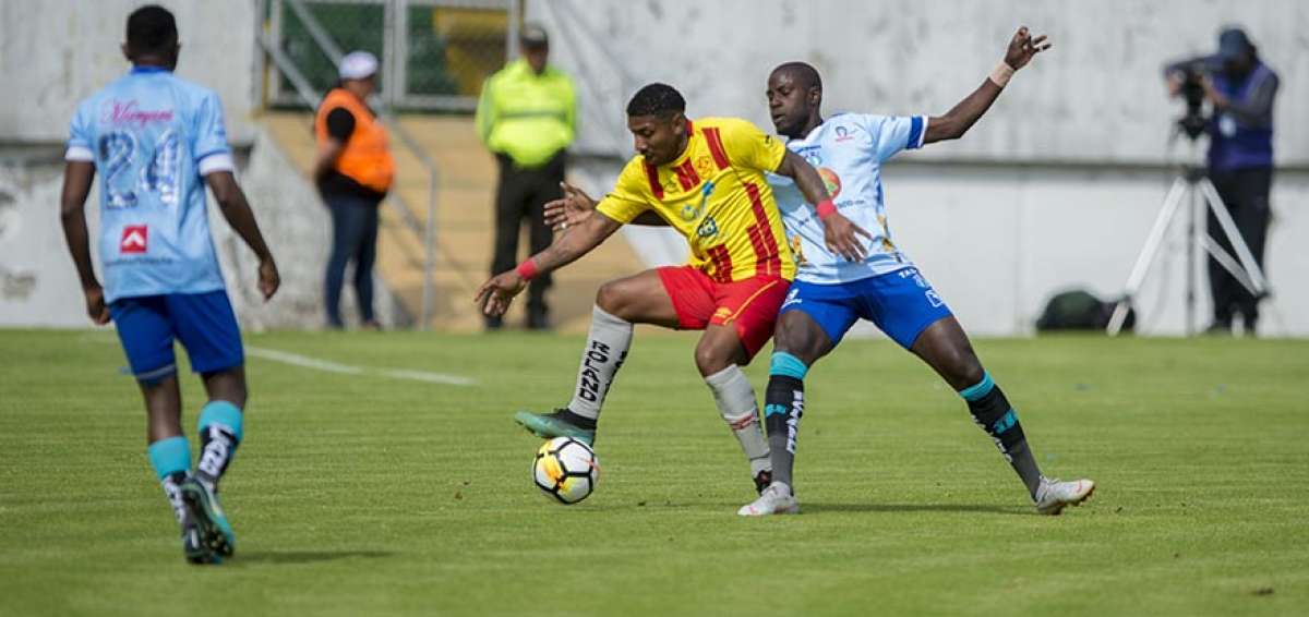Juan Govea (amarillo), de Aucas, disputa el bal&oacute;n ante la marca de dos jugadores de Macar&aacute;, en el estadio Gonzalo Pozo Ripalda de Quito.