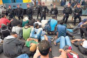 Polic&iacute;as antidisturbios, ubicados en la v&iacute;a, impiden que los migrantes se suban a los trenes, en Budapest. Foto: AFP